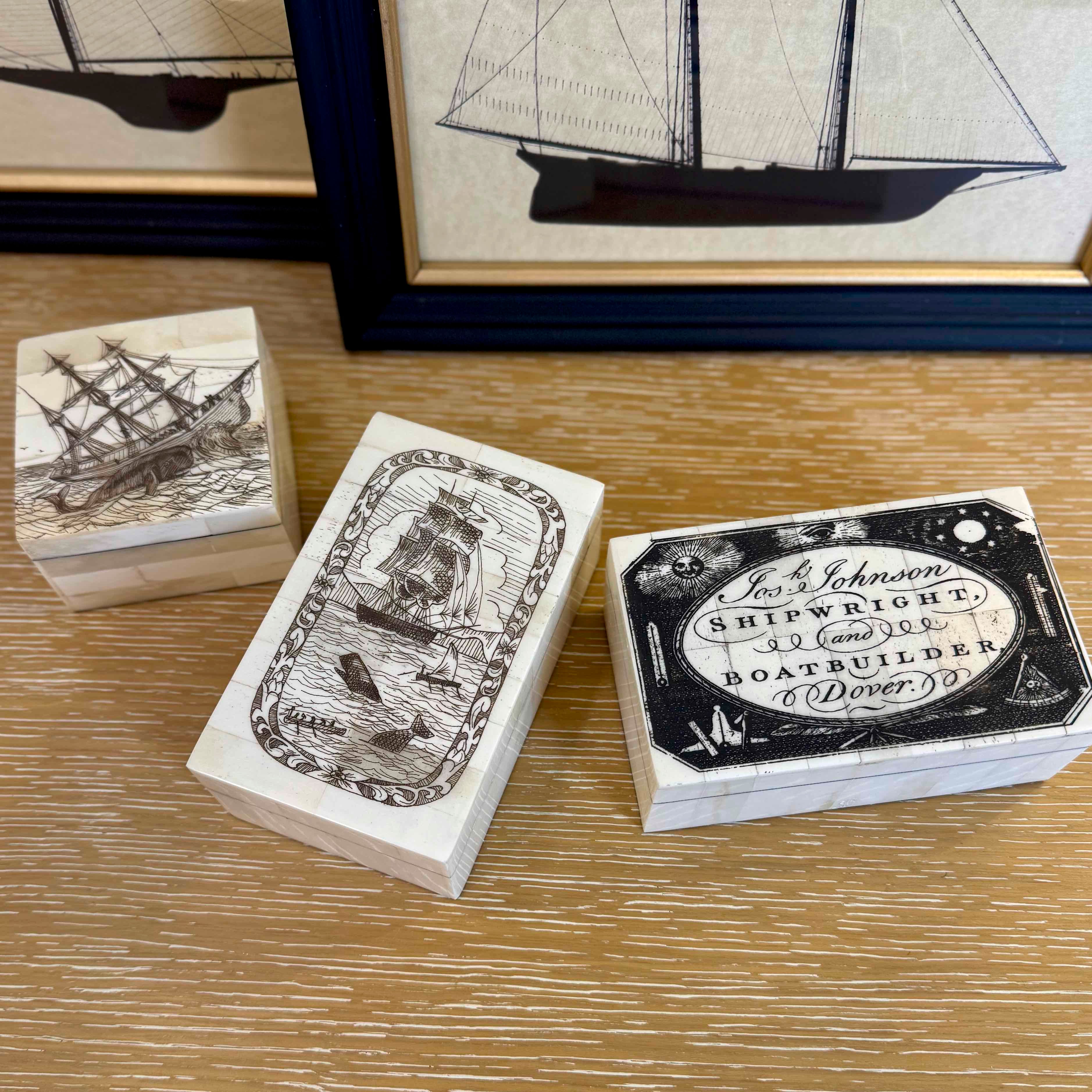Three wooden boxes with ship illustrations on a wooden surface.
