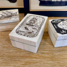 White boxes with black illustrations on a wooden surface