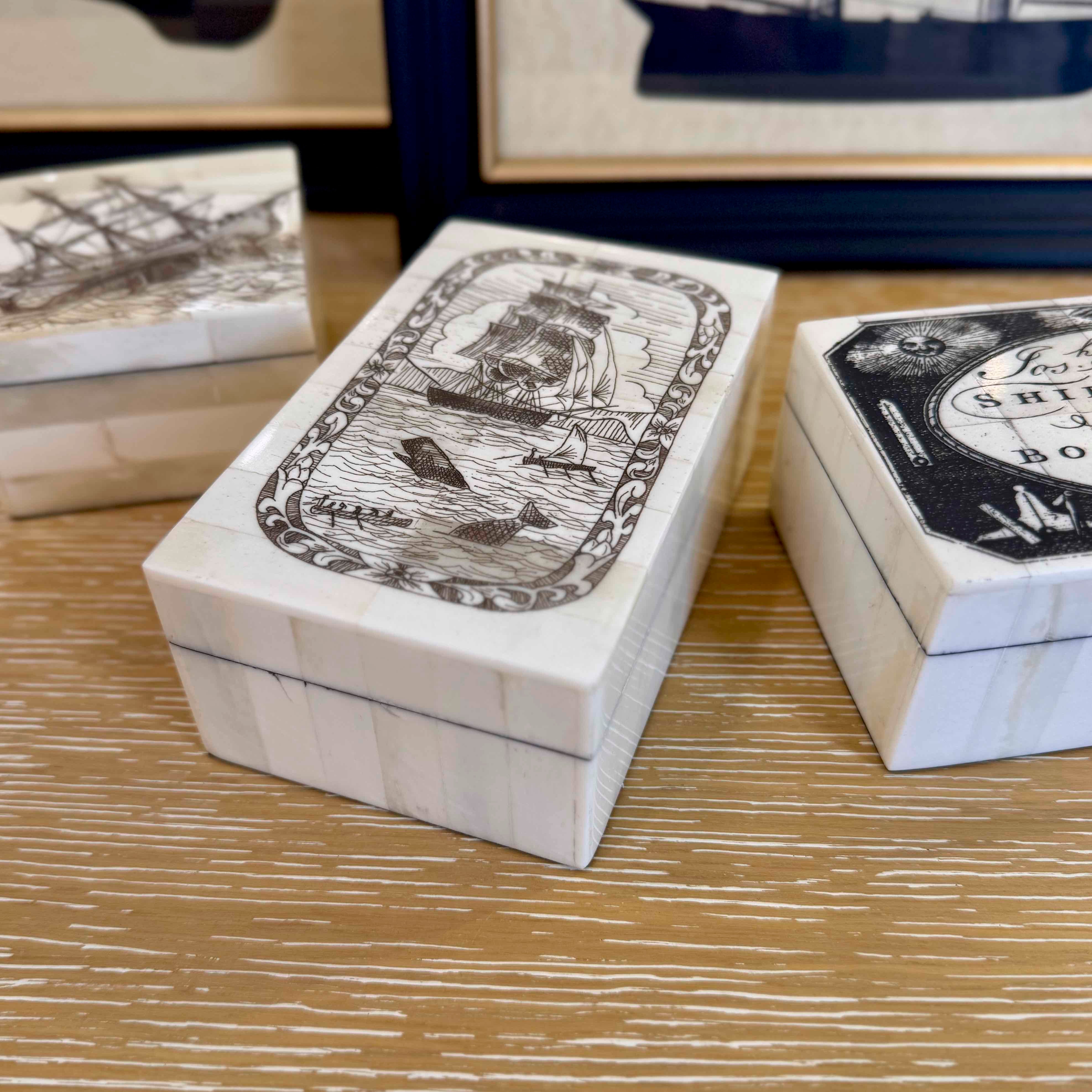 White boxes with black illustrations on a wooden surface