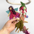 Handmade fairy dolls hanging from a circular wooden frame against a white background