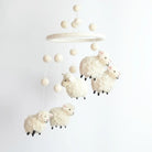 Baby mobile with sheep toys hanging from a wooden ring on a white background