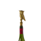Gold owl-shaped bottle stopper on a wine bottle with a white background