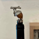 Decorative wine bottle stopper with acorn design on a plain background