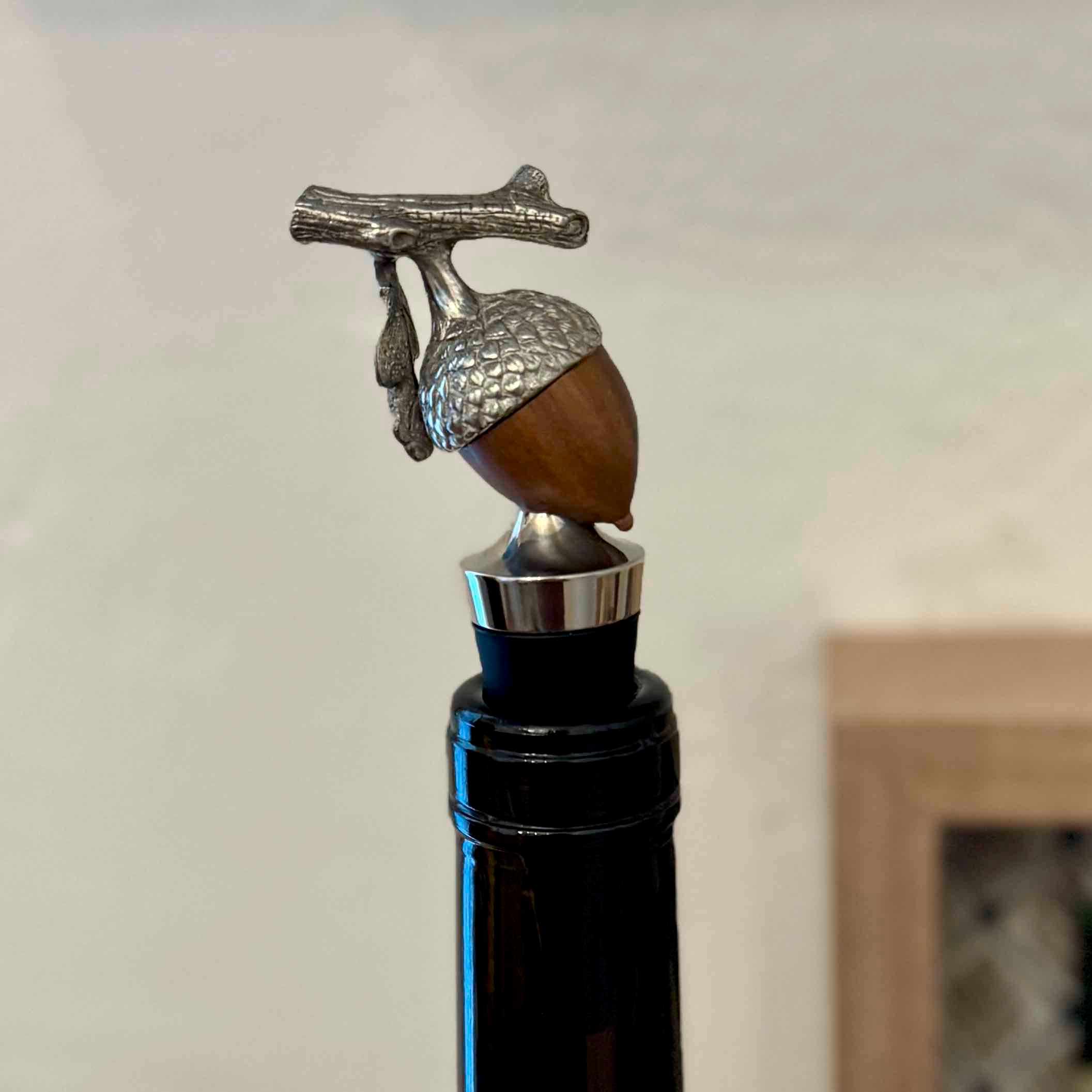 Decorative wine bottle stopper with acorn design on a plain background