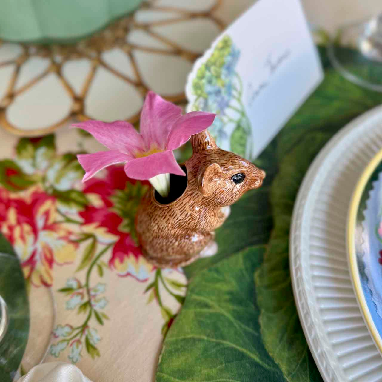 Decorative mouse with a pink flower on a floral tablecloth