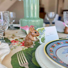 Decorative table setting with a small animal figurine on a floral place mat.