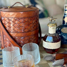 Bottle of Johnnie Walker Blue Label whisky with a leather cooler and glasses on a table.