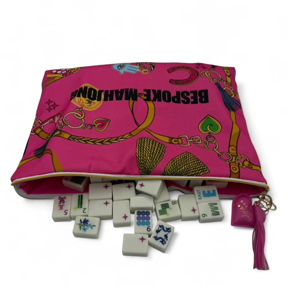Pink bag with gold patterns containing a set of white tiles with colorful designs on a white background