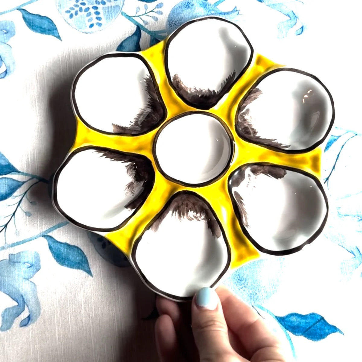 Yellow ice cube tray with paw print design held by a hand against a floral background