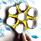 Yellow ice cube tray with paw print design held by a hand against a floral background